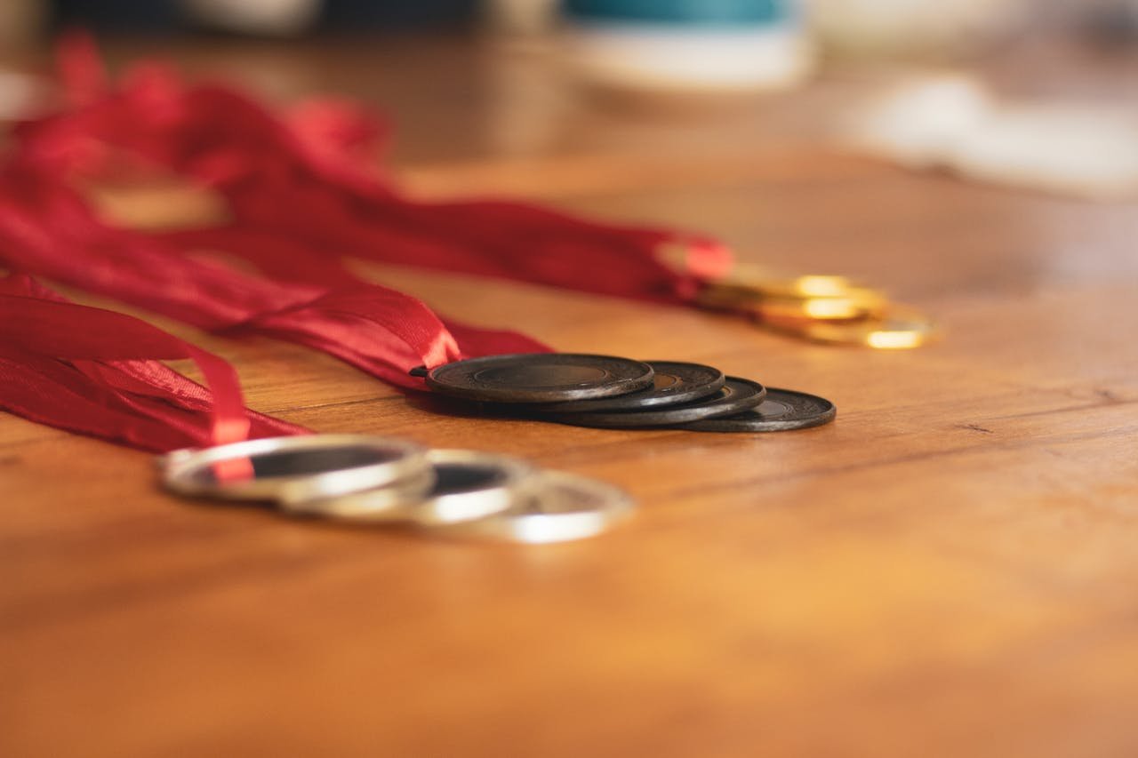 Close-up of gold, silver, and bronze medals with red ribbons on a wooden table.